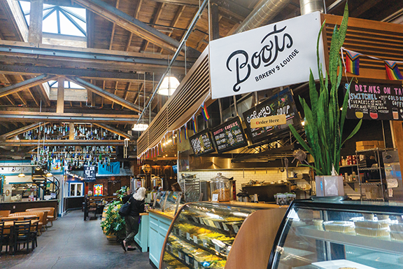 photo depicts the open area of Boots Bakery in Saranac Commons a white sign with dark brown lettering says Boots Bakery in front of the bakery counter